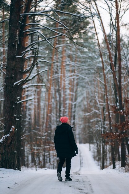 雪に囲まれた森の真ん中の道に立つ男