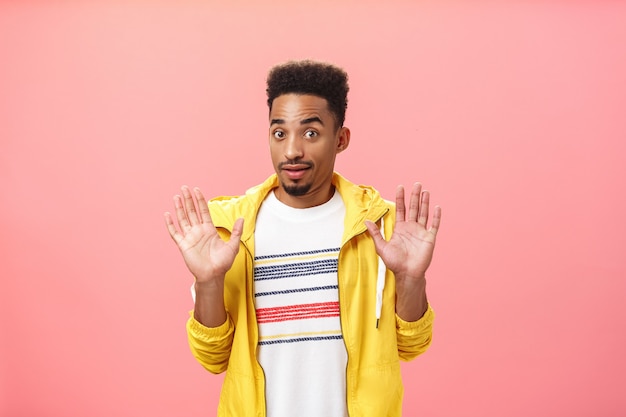 Free photo guy staying out of troubles. portrait of confused unsure clueless african american guy with beard raising palms in surrender gazing innocent at camera denying everything being unvinvolved.