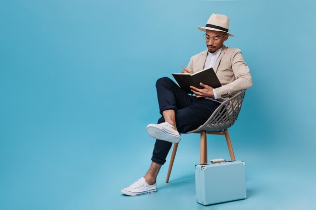 Guy in suit sits on chair and holds book