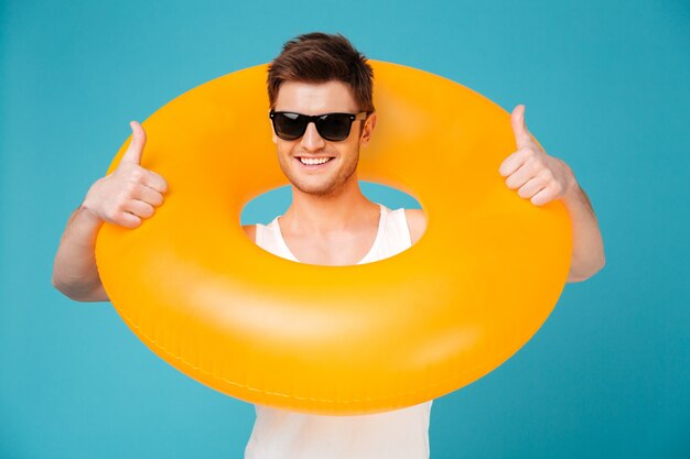 Guy in sunglasses holding inflatable ring aroung his neck