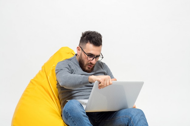 Free photo guy suprised while sitting on yellow pouf chair