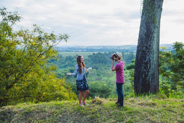 Guy taking photo of girlfriend in countryside
