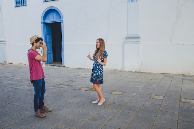 Free photo guy taking photo of girlfriend in front of a house