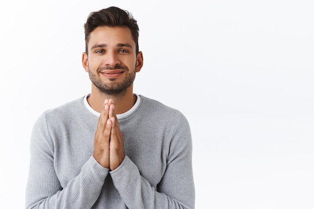 Free photo guy thanking for delicious meal, holding hands in pray in begging pose, smiling delighted, supplicating, asking for offer or express gratitude for help