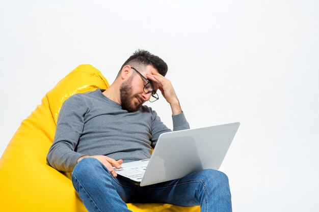 Guy in thoughts while sitting on yellow pouf chair