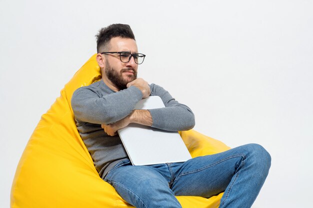 Guy in thoughts while sitting on yellow pouf chair