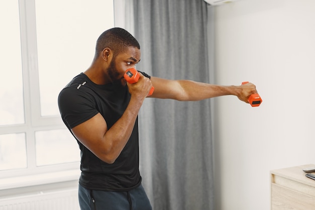 Guy training at home with dumbbells