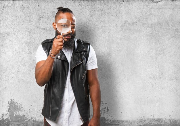 Guy using a magnifying glass with wall background