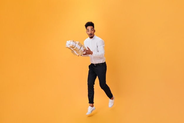 Guy in white shirt and black pants bounces with gifts