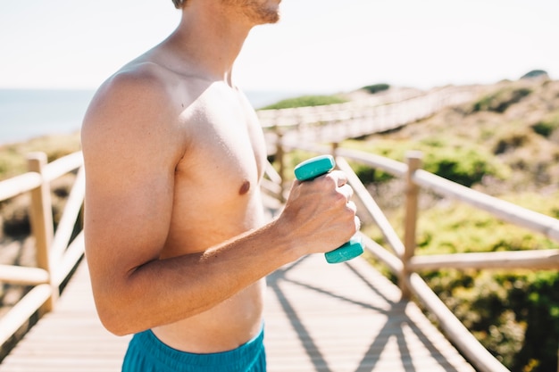 Guy with dumbbell at the beach