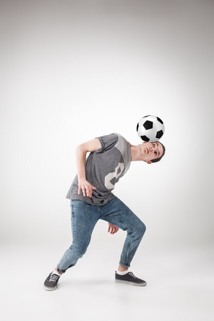 парень с футбольным мячом на сером