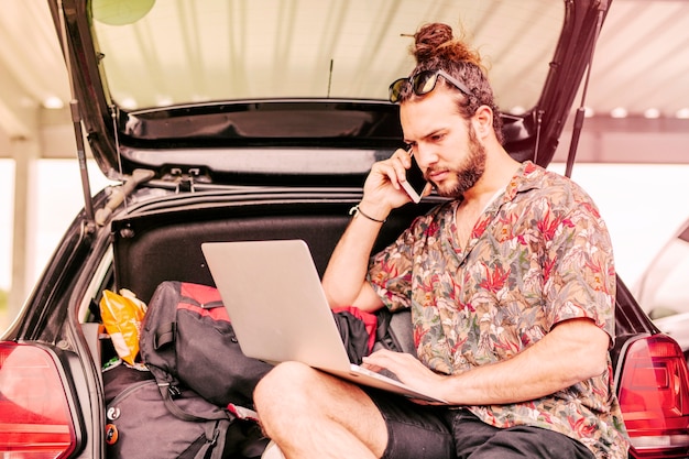 Free photo guy with laptop and smartphone near car