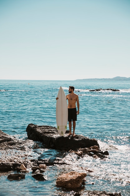 Guy with white surfboard on stone