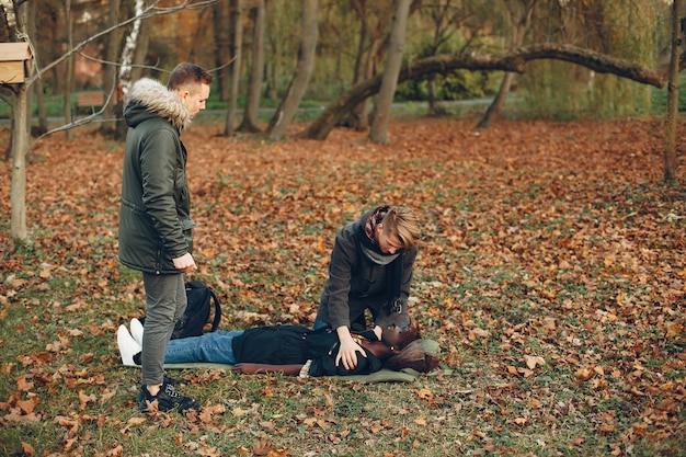 Guys help a woman. African girl is lying unconscious. Providing first aid in the park.