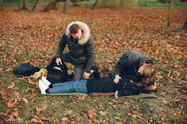 Free photo guys help a woman. african girl is lying unconscious. providing first aid in the park.