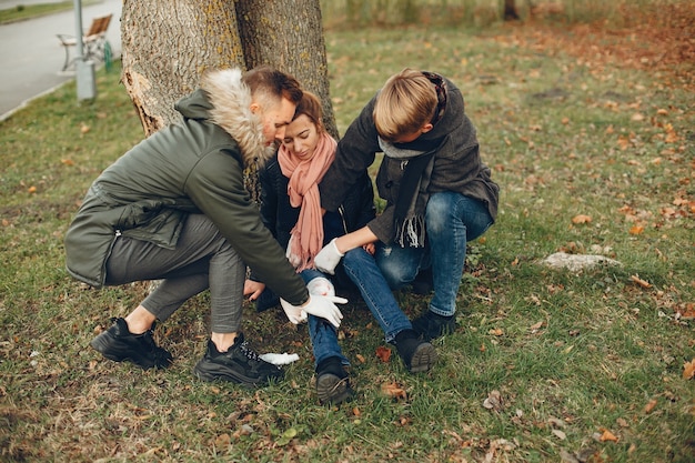 Free photo guys help a woman. girl with a broken leg. providing first aid in the park.