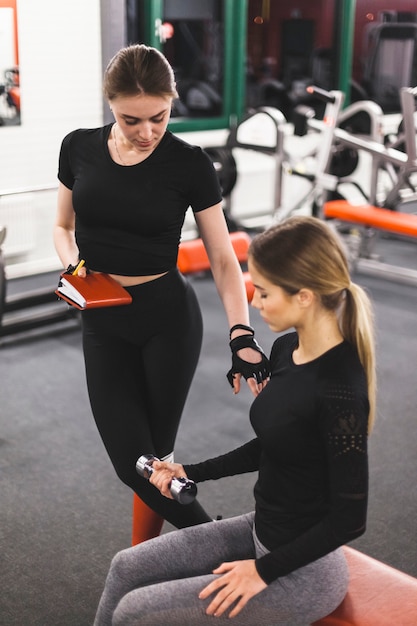 Free photo gym instructor guiding woman while exercising with dumbbell