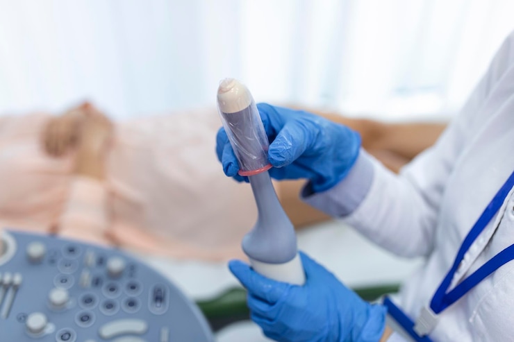 Free Photo gynecologist places ultrasound probe cover on a transvaginal ultrasound scanner for vaginal examination of a woman
