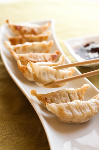 Gyoza and chopsticks on white plate