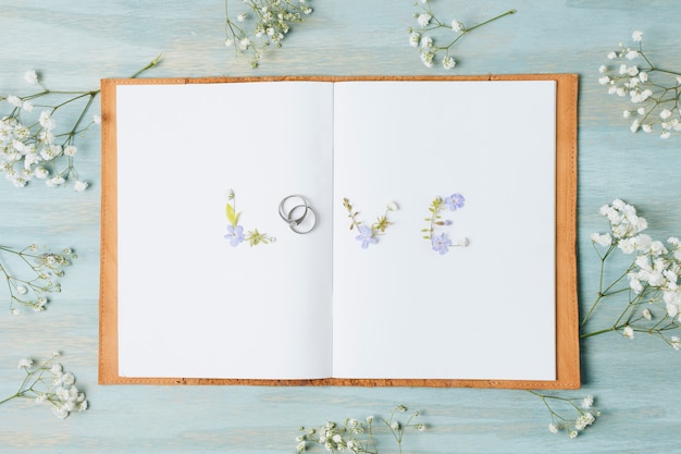 Gypsophila flower around the love text on white page book over the wooden desk