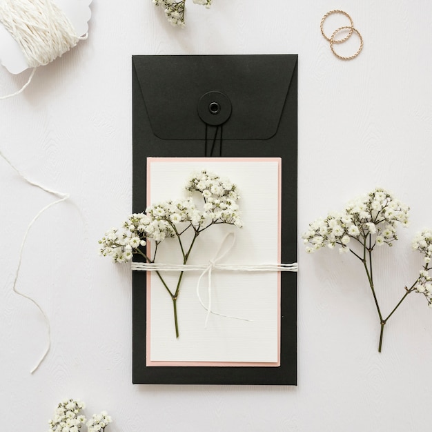 Gypsophila and greeting card tied with strings on white backdrop