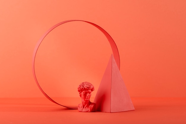 Foto gratuita busto in gesso su fondo corallo con forme geometriche