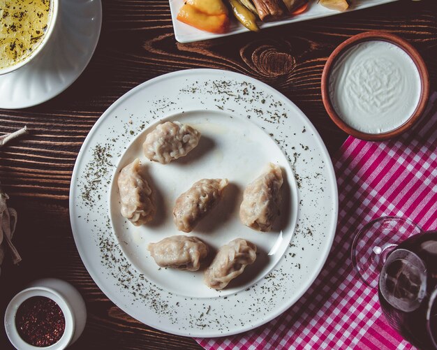 Gyurza on a white plate with sumac and sour cream