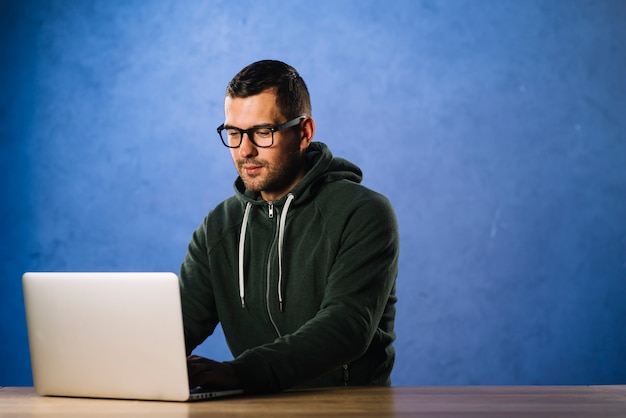 Hacker with glasses looking at laptop