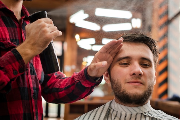 Foto gratuita parrucchiere che spruzza i capelli del cliente