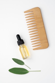 Hair care set. wooden comb, hair oil. white background, top view.