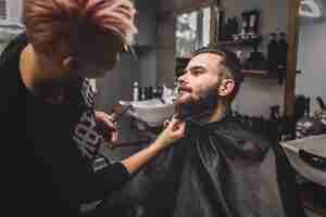 Foto gratuita parrucchiere taglio barba del cliente