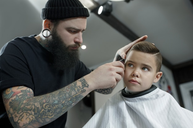 Hairdresser cutting little boy's hair
