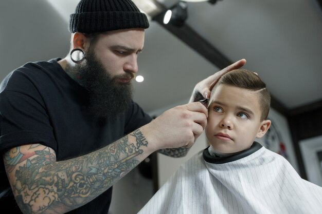美容師が小さな男の子の髪をカット