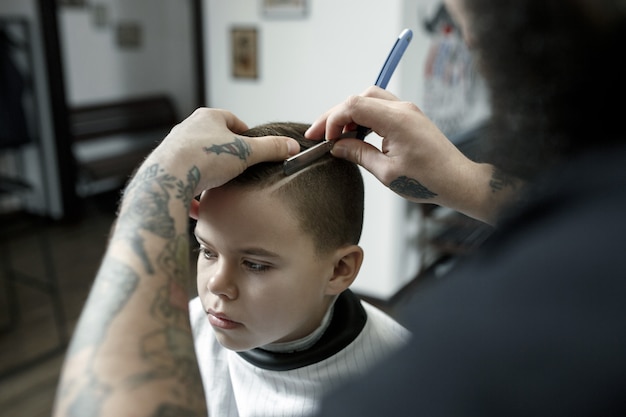 Hairdresser cutting little boy's hair