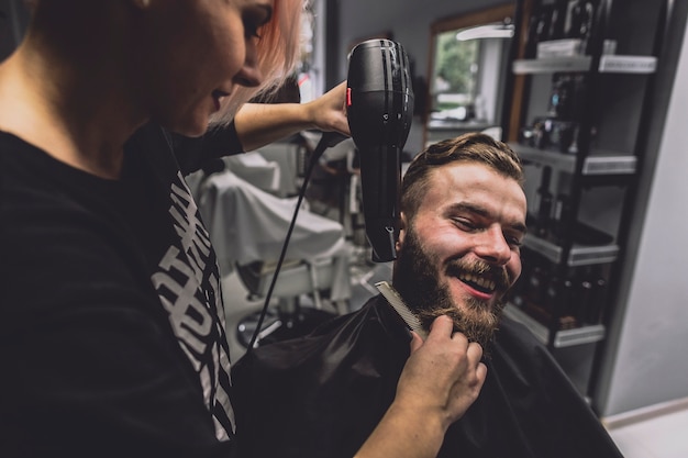 Hairdresser drying beard of handsome man