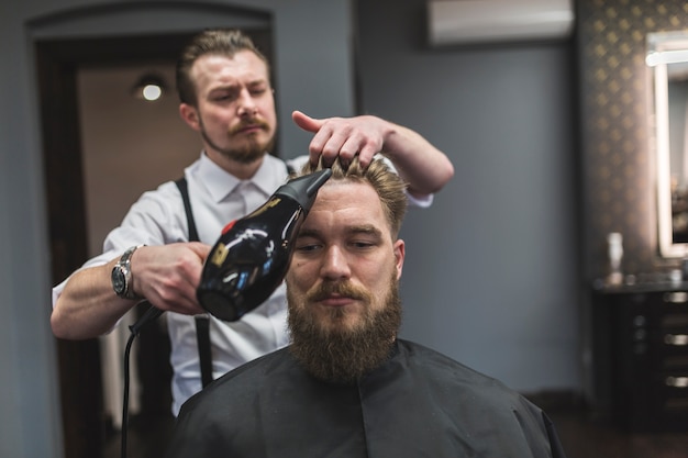 ひげのある男の毛髪を乾燥させるヘアドライヤー