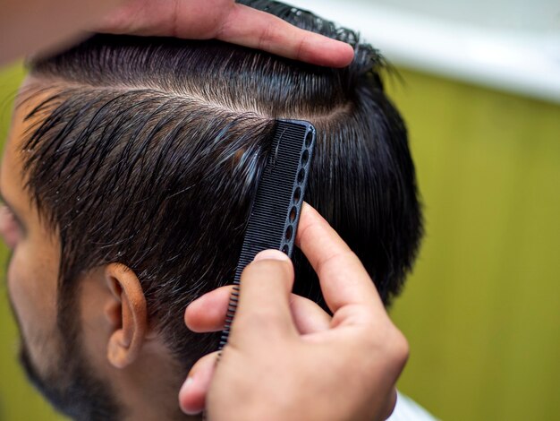 Парикмахер делает укладку волос на волосы своего клиента