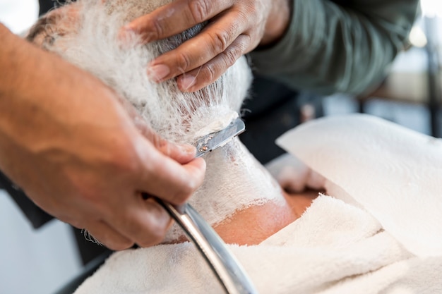 Парикмахер для бритья бороды клиенту