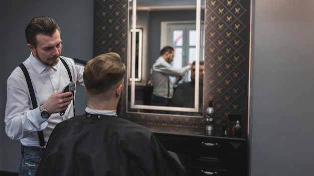 Hairdresser shaving client near mirror