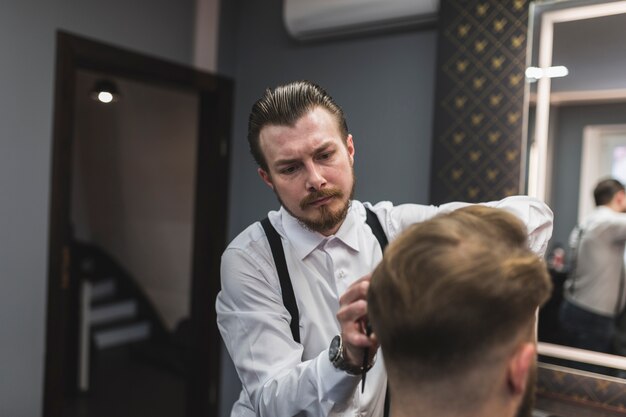Hairdresser styling hair of man