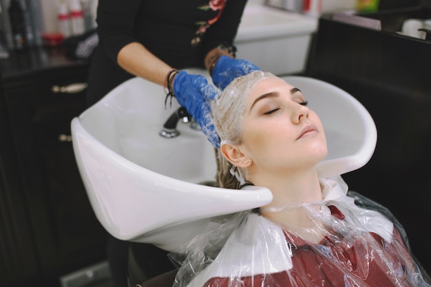 Hairdresser washing head of woman