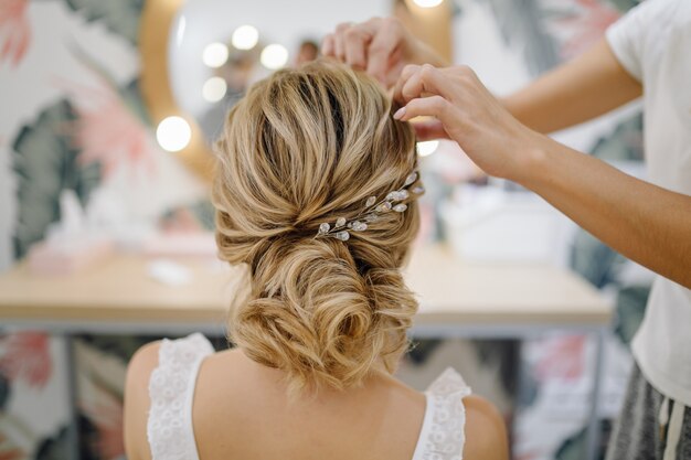 Hairdresser woman weaving braid hair, wedding styling.