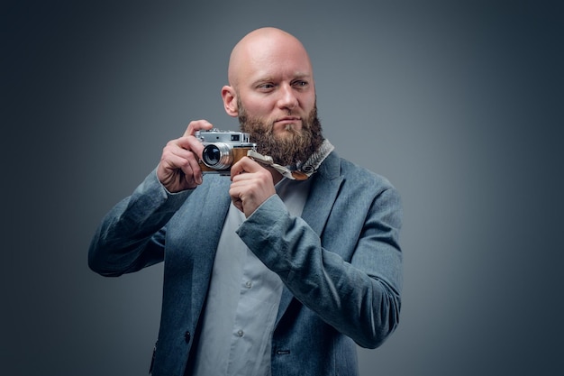 Hairless bearded male shooting with vintage SLR photo camera.