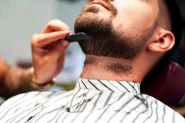 顧客のひげをとかすヘアスタイリスト