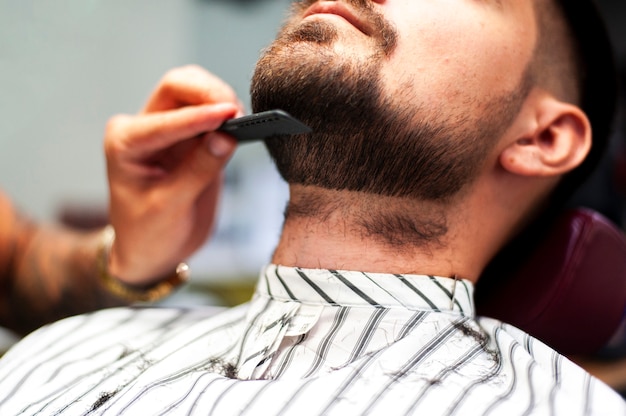 Hairstylist combing customer beard