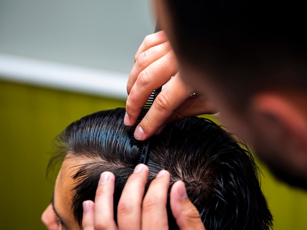 Hairstylist combing customer hair