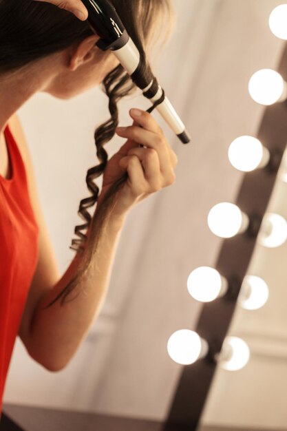 Hairstylist curling hair client in hairdressing salon