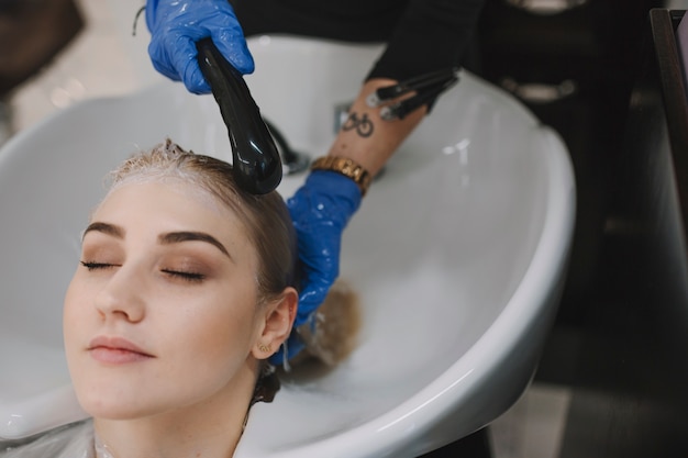 Hairstylist washing client hair in sink