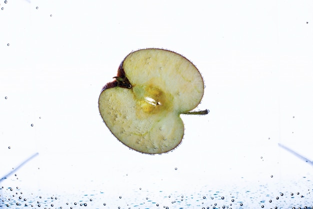 Free photo half of apple floats in aquarium with white background