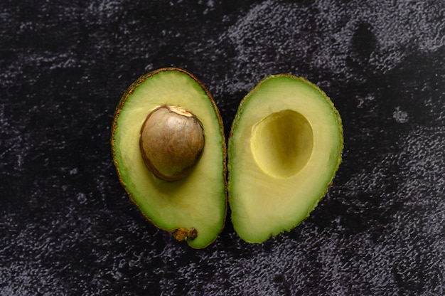 Half avocado on the black cement floor.